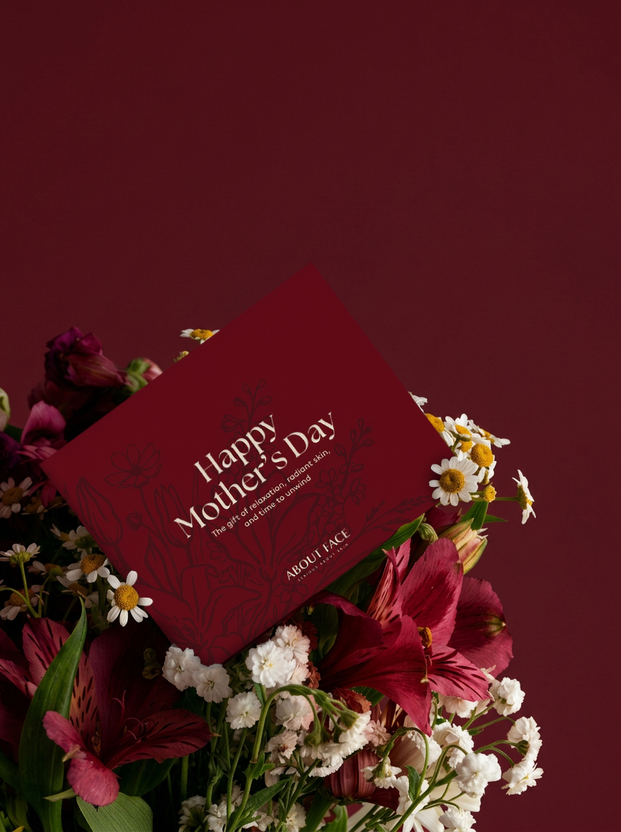 About Face Happy Mother’s Day card arranged among deep red flowers